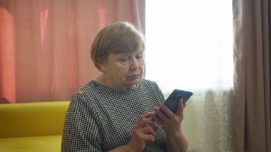 Üst düzey kadın evde akıllı telefondan arıyor ve konuşuyor.