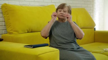 Kıdemli kadın gözlüğünü ayarlıyor ve rahat bir şekilde sarı koltukta otururken kitap okumaya başlıyor.