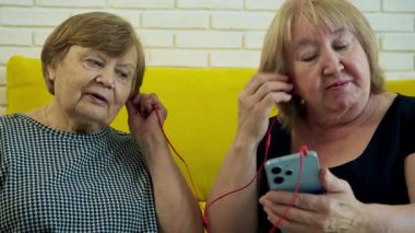 Kulaklık takan, akıllı telefondan müzik dinleyen ve şarkıyı tartışan iki son sınıf öğrencisi kadın.