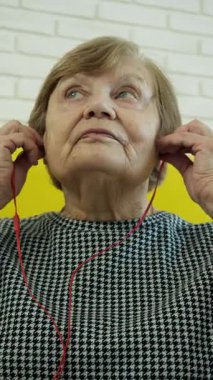 Müzik dinleyen ve akıllı telefondan konuşan yaşlı bir kadın.