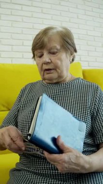 Son sınıf öğrencisi kadın gözlüğünü takıyor ve sarı koltukta oturmuş kitap okumaya başlıyor.