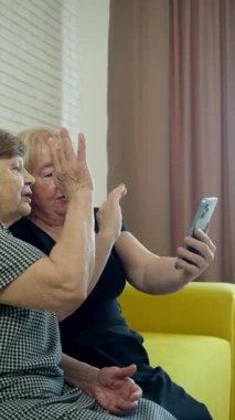 İki son sınıf öğrencisi bir kanepede oturmuş, akıllı telefona bakıyor ve içeriğini tartışıyorlar.