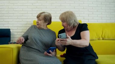 İki son sınıf öğrencisi kanepede oturmuş akıllı telefonlara bakıyor ve bir şeyler tartışıyorlar.