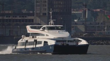 Portekiz 'in Lizbon şehrinde Portekiz bayrağı dalgalanan Tagus Nehri' nde yüzen modern katamaran feribotu.
