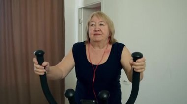 Üst düzey kadın ev çalışması için eliptik antrenör kullanıyor.