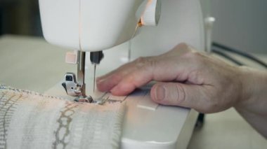 Dikiş makinesinin iğnesinin altındaki kumaşa rehberlik eden elleri kapat