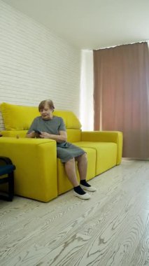 Kıdemli kadın modern teknolojiden hoşlanır, rahat bir şekilde etrafı kolaçan eder ve canlı oturma odasından iletişim kurar.