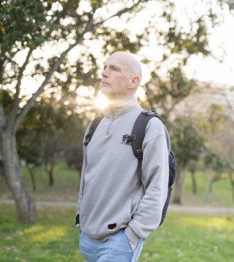 Sırt çantalı son sınıf öğrencisi altın saatinde parkta günbatımının keyfini çıkarıyor.