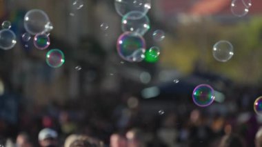 Yanardöner sabun köpükleri bulanık kalabalığın üzerinde süzülüyor.