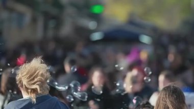 Sabun köpükleri, açık havada eğlenen büyük bir kalabalığın üzerinde yüzer.