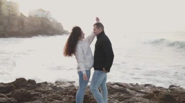 Romantik çift şafak vakti kayalık bir sahilde hassas anların tadını çıkarıyor.