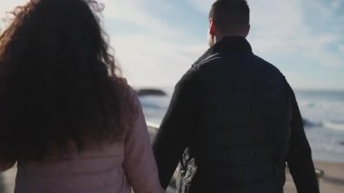 Sahilde yürüyüş yapan romantik bir çift.