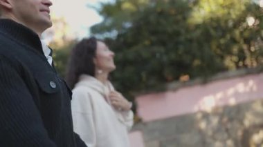 Güneşli bir günde sokakta yürüyen mutlu bir çift.