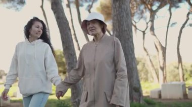 Yaşlı büyükannenin elini tutan mutlu torun parkta birlikte yürüyor.