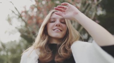Gençlik saçlarıyla oynuyor ve sonbaharda parkta gülümsüyor.