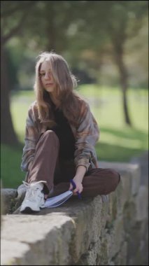 Öğrenci öğreniyor ve parkta notlar alıyor.