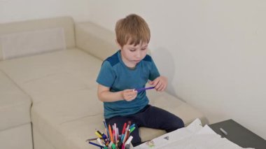 Koltukta oturan çocuk renkli kalemlerle küçük masaya yerleştirilmiş.