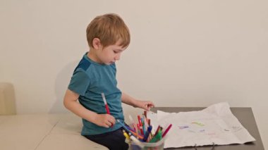 Kreş araştırmacısı yaratıcılığı keşfediyor, beyaz kağıda çeşitli işaretlerle renkli resimler çiziyor.