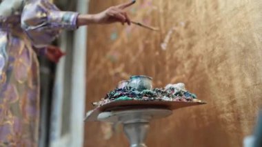 Kadın sanatçı fırçayla altın duvarı boyuyor