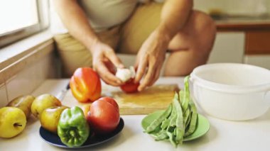 Şef sarımsak karanfili soyuyor tahtaya taze sebzeler koyuyor.