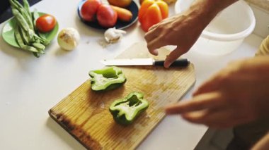 Şef yeşil dolmalık biber hazırlıyor, kesiyor ve tabağa koyuyor.