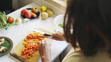 Şef malzemeleri hazırlıyor, ağaç kesme tahtasında dolma biber doğruyor.