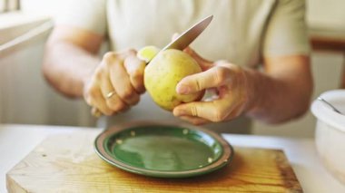 Tahta kesme tahtasındaki bıçakla patates soyan eller.