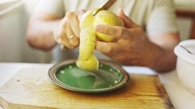 Şef, tahta kesme tahtasına bıçakla patates soyuyordu.