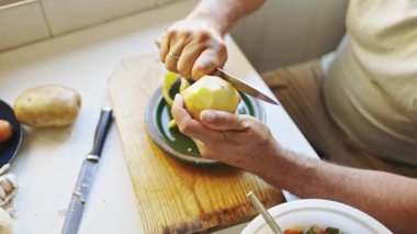 Şef, tahta kesme tahtasına bıçakla patates soyuyordu.