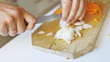 Şef ahşap kesme tahtasıyla soğan doğruyor.