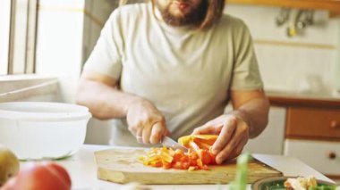 Profesyonel şef ahşap kesme tahtasında taze dolma biber dilimliyor, lezzetli bir yemek için malzemeler hazırlıyor.