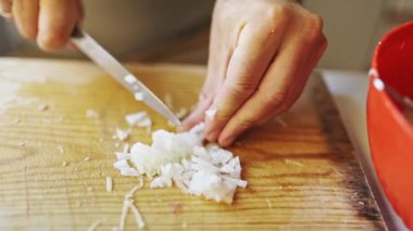 Beyaz soğan ahşap kesim tahtasındaki şef tarafından ince ince doğranır.