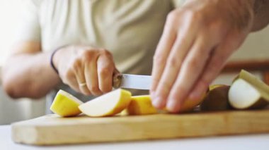 Şef ahşap kesim tahtasına armut dilimler, lezzetli bir yemek için malzeme hazırlar.
