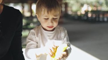 Sevimli çocuk, annesiyle birlikte açık hava piknik masasında soyulup muz yemekten hoşlanıyor.