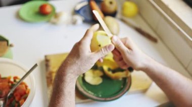 Şef mutfaktaki tahta kesme tahtasının üzerinde bıçakla patates soyuyordu.