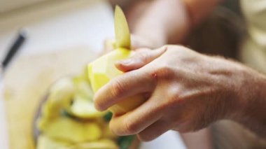 Şef, patatesleri kesme tahtasıyla soyar, yemek malzemelerini hazırlar.