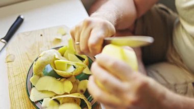 Şef tahta kesme tahtasındaki bıçakla patates soyuyordu.