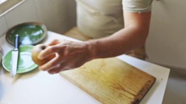 Şef, ahşap bir kesme tahtasındaki elmayı dikkatlice dilimliyor. Lezzetli bir mutfak yaratımı için malzemeleri hazırlıyor.