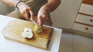 Ahşap kesme tahtasında yeşil elma dilimleyen şef.