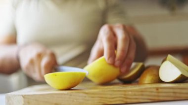 Aşçıların elleri ahşap bir kesme tahtasıyla altın bir elmayı keserken.