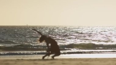 Genç kadın batımında sahilde dans