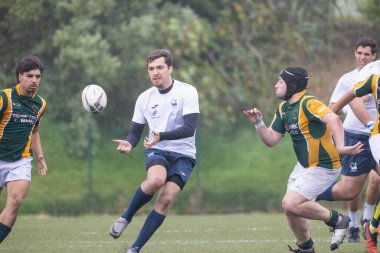 3 Mayıs 2025, Lisbon. Portekiz - oeiras vs ag - rugby oyuncuları yağmurlu bir günde bir maçta yarışıyor, bir oyuncu topa vuruyor