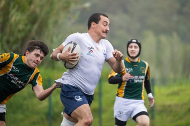 3 Mayıs 2025, Lisbon. Portekiz - oeiras vs ag - yağmurlu bir maçta rakipler tarafından kovalanan rugby oyuncusu