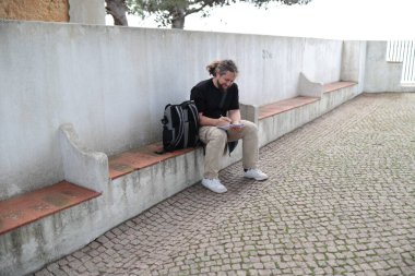 Turist seyahat planlarını not ederken dinleniyor.