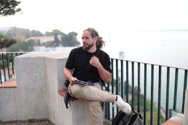 Not defterine notlar yazan yaratıcı adam Portekiz, Lizbon 'daki Tagus Nehri' nin ilham verici manzarasının keyfini çıkarıyor.