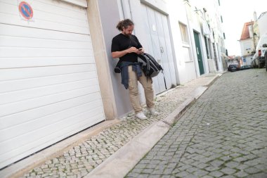 Lizbon, Portekiz 'de bir kaldırım taşı caddesinde akıllı telefon kullanan erkek turist