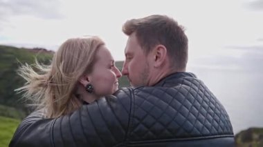 Sevgi dolu bir çift, okyanus manzarasının tadını çıkararak, manzaralı bir uçurumda samimi anlar paylaşır.