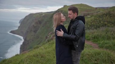 Güzel bir okyanusa bakan bir uçurumda romantik bir anın tadını çıkaran turistler.
