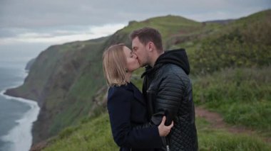 Turistler okyanusa bakan bir uçurumda romantik bir anın tadını çıkarıyorlar.