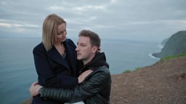 Uçurumun kenarında kucaklaşan çiftler birbirlerine yürekten bakıyorlar. Sahne, çarpıcı bir okyanus zeminine karşı derin bir duygusal bağlantı yakalıyor.